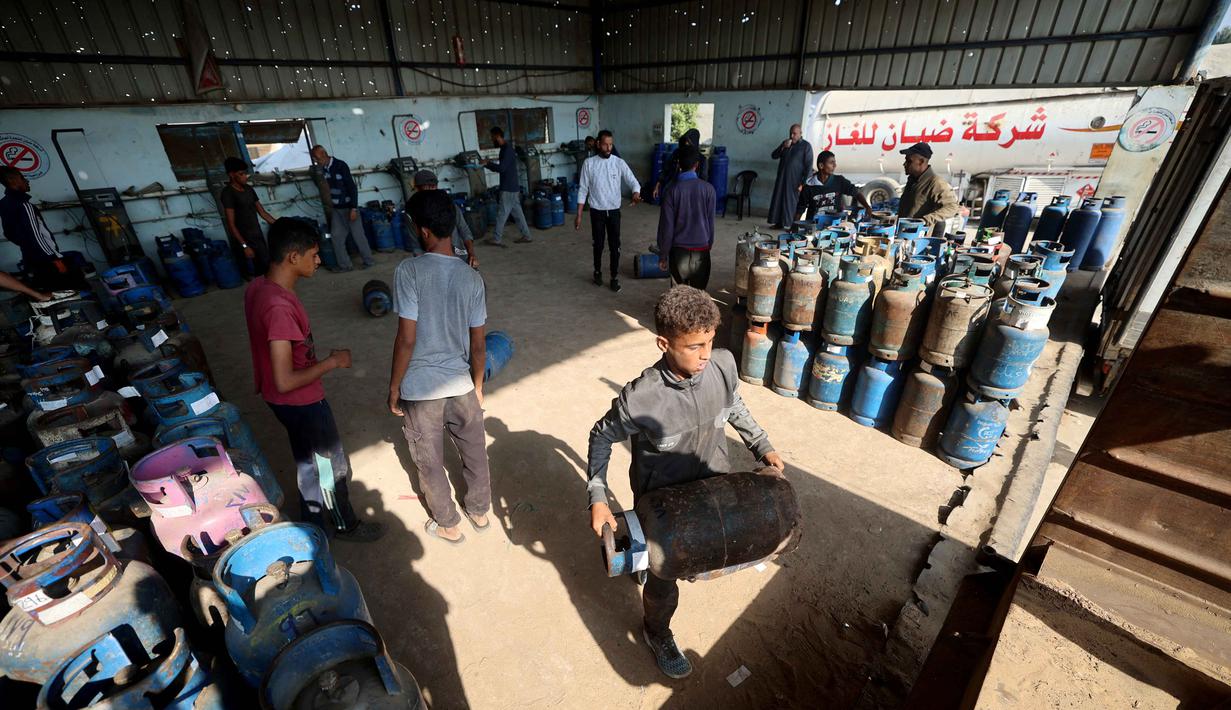 Diketahui, sebelum blokade Israel diperketat, otoritas pendudukan hanya mengizinkan sekitar 10 truk gas per hari masuk melalui Kerem Shalom dengan membawa sekitar 200 ton gas, atau kurang dari separuh kebutuhan harian Gaza. Tampak dalam foto, pekerja Palestina memuat tabung gas setelah diisi untuk pertama kalinya dalam setahun, di stasiun pengisian resmi di kamp pengungsi Nuseirat, di bagian tengah Jalur Gaza, pada 10 November 2025. (Eyad Baba/AFP)