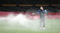 Petugas menyemprotkan disinfektan ke lapangan untuk menghentikan penyebaran virus corona COVID-19 jelang pertandingan sepak bola putaran pertama grup C putra Olimpiade Tokyo 2020 antara Argentina dan Australia di Sapporo Dome, Sapporo, Jepang, Kamis (22/7/2021). (ASANO IKKO/AFP)