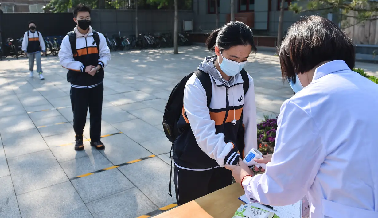 Sejumlah siswa mengantre sambil menjaga jarak untuk menjalani pemeriksaan suhu tubuh di Sekolah Menengah Atas No. 161 Beijing, Beijing, China, Senin (27/4/2020). Sekolah menengah atas di Beijing memulai kembali kegiatan belajar di kelas untuk siswa tingkat akhir. (Xinhua/Peng Ziyang)