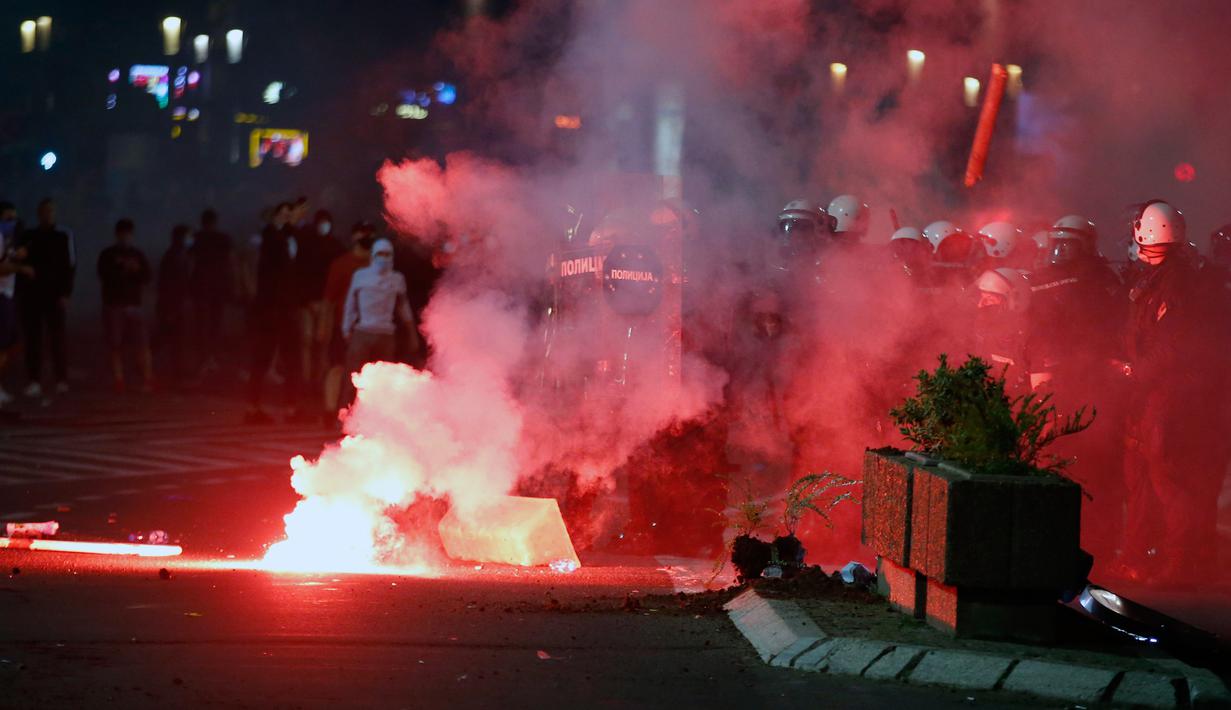 Aparat kepolisian Serbia bentrok dengan pengunjuk rasa di dekat gedung parlemen di Beograd, Selasa (7/7/2020). Ribuan pengunjuk rasa marah setelah pemerintah mengeluarkan keputusan untuk memberlakukan kembali jam malam akibat melonjaknya kasus Covid-19. (AP/Marko Drobnjakovic)