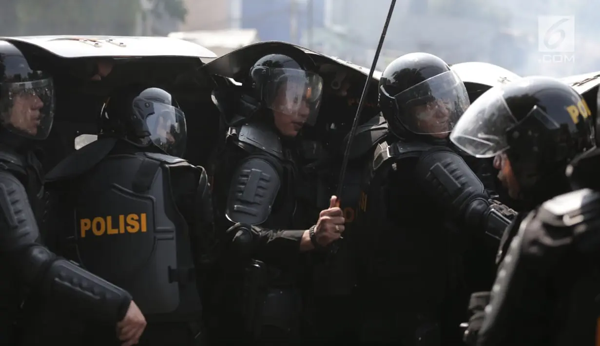 Polisi berlindung saart terjadi bentrok dengan massa aksi demo di Petamburan, Jakarta Barat, Rabu (22/5/2019). Situasi ricuh tersebut masih dalam pengamanan pihak kepolisian. (Liputan6.com/Faizal Fanani)