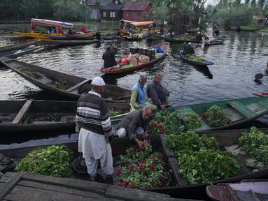Laki-laki Kashmir menjual produk mereka di pasar sayuran terapung di Danau Dal, Srinagar, Kashmir yang dikuasai India, Kamis (7/4/2022). (AP Photo/Rajesh Kumar Singh)