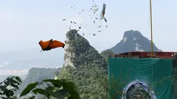 Penerjun melompat dari atas tebing mengenai target sasaran saat mengikuti Kejuaraan Dunia Wingsuit di pegunungan Tianmenshan, China, 11 September 2017. Wingsuit adalah salah satu varian baru paragliding, dengan kostum yang dilengkapi sayap.  (STR / AFP)