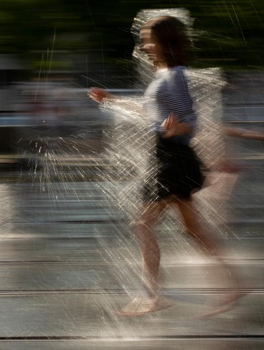Seorang gadis berlari mendinginkan dirinya berlari di air mancur di sebuah taman di Moskow, Rusia, (3/8). Cuaca panas di Moskow terus berlanjut, dengan suhu diperkirakan mencapai 30 derajat Celcius (86 Fahrenheit). (AP Photo/Alexander Zemlianichenko)