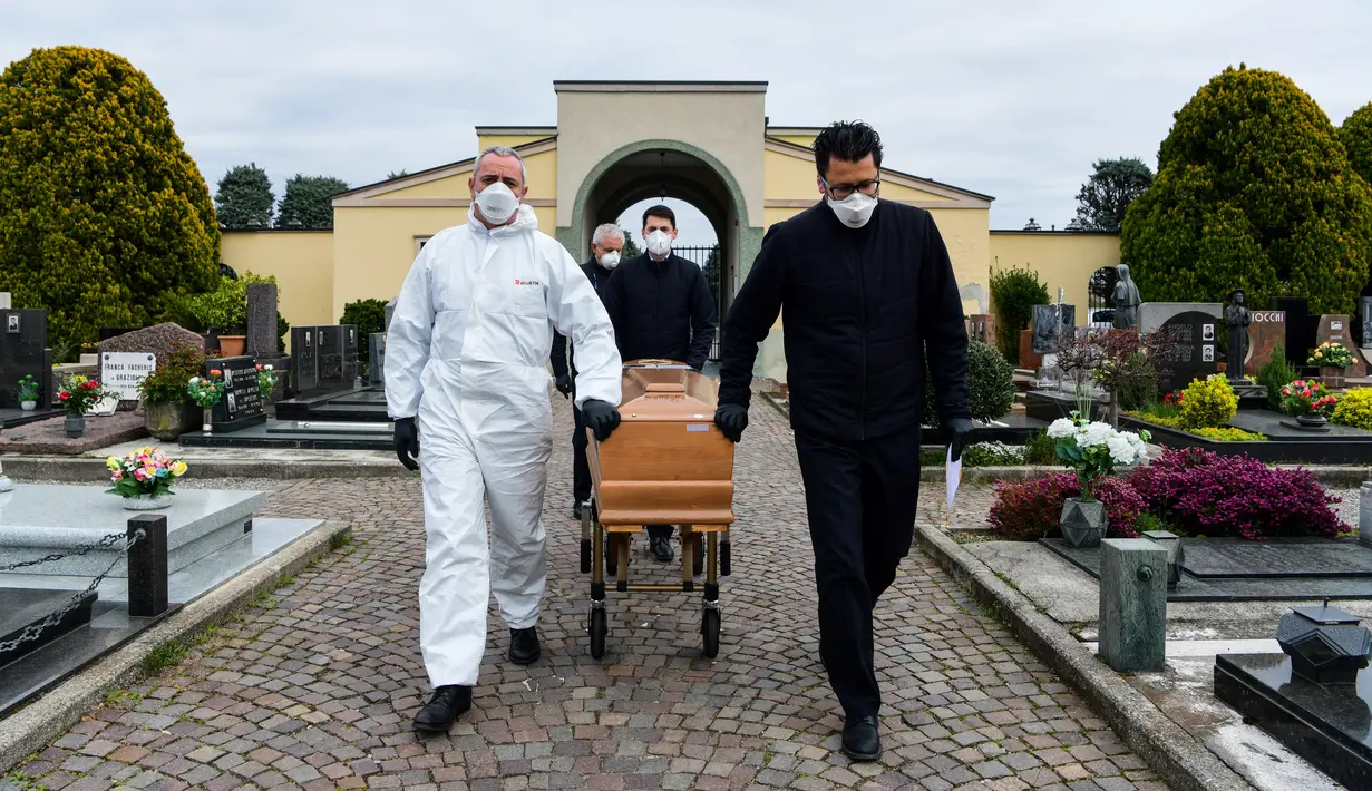 Pengusung jenazah membawa peti mati seorang warga yang meninggal akibat virus corona untuk upacara pemakaman tanpa kehadiran dari sanak saudaranya yang sedang menghadapi karantina selama masa lockdown di pemakaman Grassobbio, Lombardy, Italia, Senin (23/3/2020). (Piero CRUCIATTI / AFP)