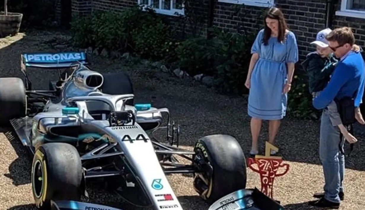 Bocah penderita kanker tulang langka Harry Shaw digendong ayahnya melihat mobil F1 yang dia terima dari Lewis Hamilton di Redhill, Surrey, Inggris, 13 Mei 2019. Mobil Mercedes dengan nomor 44 itu terparkir dengan rapih di halaman rumah Harry. (James Shaw/via REUTERS)