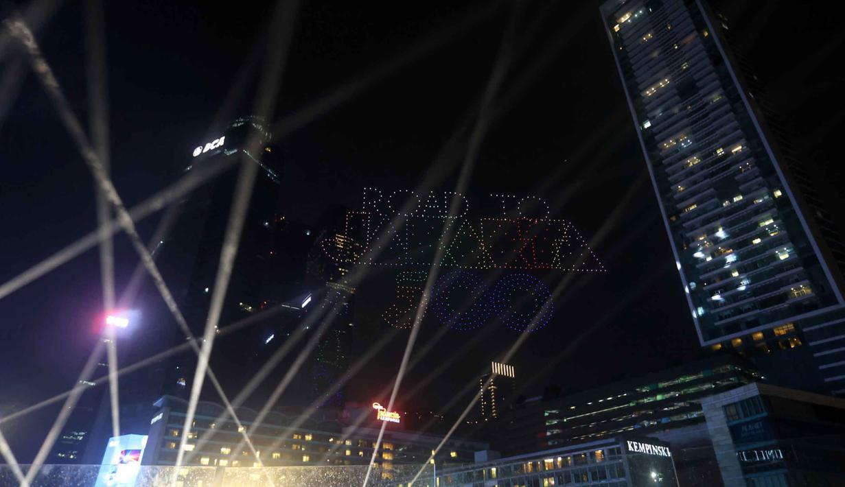 Formasi drone terlihat tepat berada di atas panggung utama perayaan tahun baru. Tampak dalam foto, warga mengabadikan pertunjukan drone saat perayaan malam pergantian tahun di kawasan Bundaran Hotel Indonesia, Jakarta, Rabu (31/12/2025). (Kapanlagi.com/Budy Santoso)
