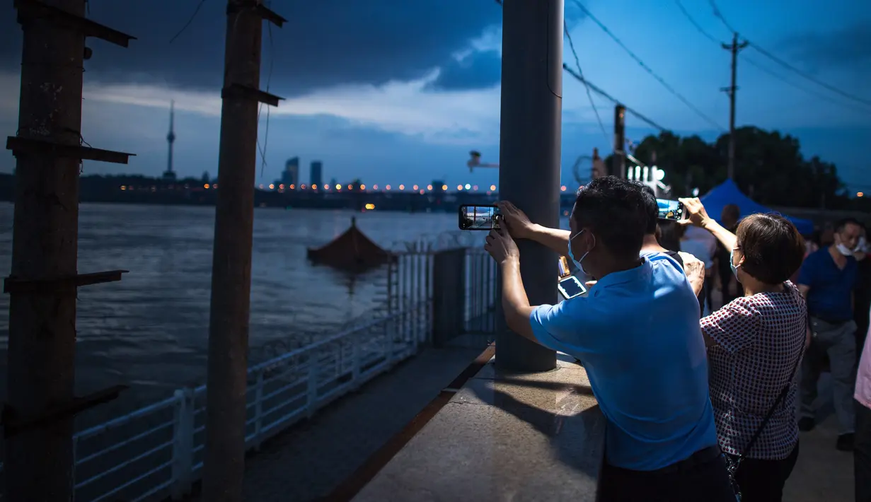 Warga memotret lokasi terendamnya sebuah paviliun akibat meningkatnya ketinggian air di Sungai Yangtze di Wuhan, Provinsi Hubei, China (13/7/2020). Ketinggian air di Sungai Yangtze di Hankou, Wuhan, turun dari level tertinggi 28,77 meter menjadi 28,74 meter pada Senin (13/7). (Xinhua/Xiao Yijiu)