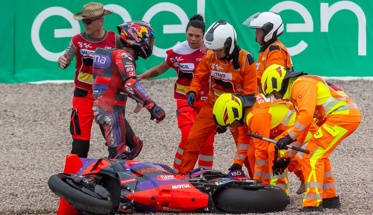 Sejumlah track marshal membantu pebalap Prima Pramac Racing Jorge Martin saat terjatuh saat menjalani MotoGP Jerman 2024 di Sirkuit Sachsenring, Jerman, Minggu (7/7/2024) waktu setempat.  (AFP/Radek Mika)