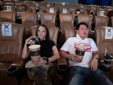 Pengunjung minum minuman ringan ketika mereka berlatih menjaga jarak sosial selama film di bioskop Paragon Cineplex di Bangkok, Thailand, Senin (1/6/2020). Mulai 1 Juni, pihak berwenang Thailand mengizinkan bioskop dan bisnis lain untuk dibuka kembali. (AP Photo/Sakchai Lalit)