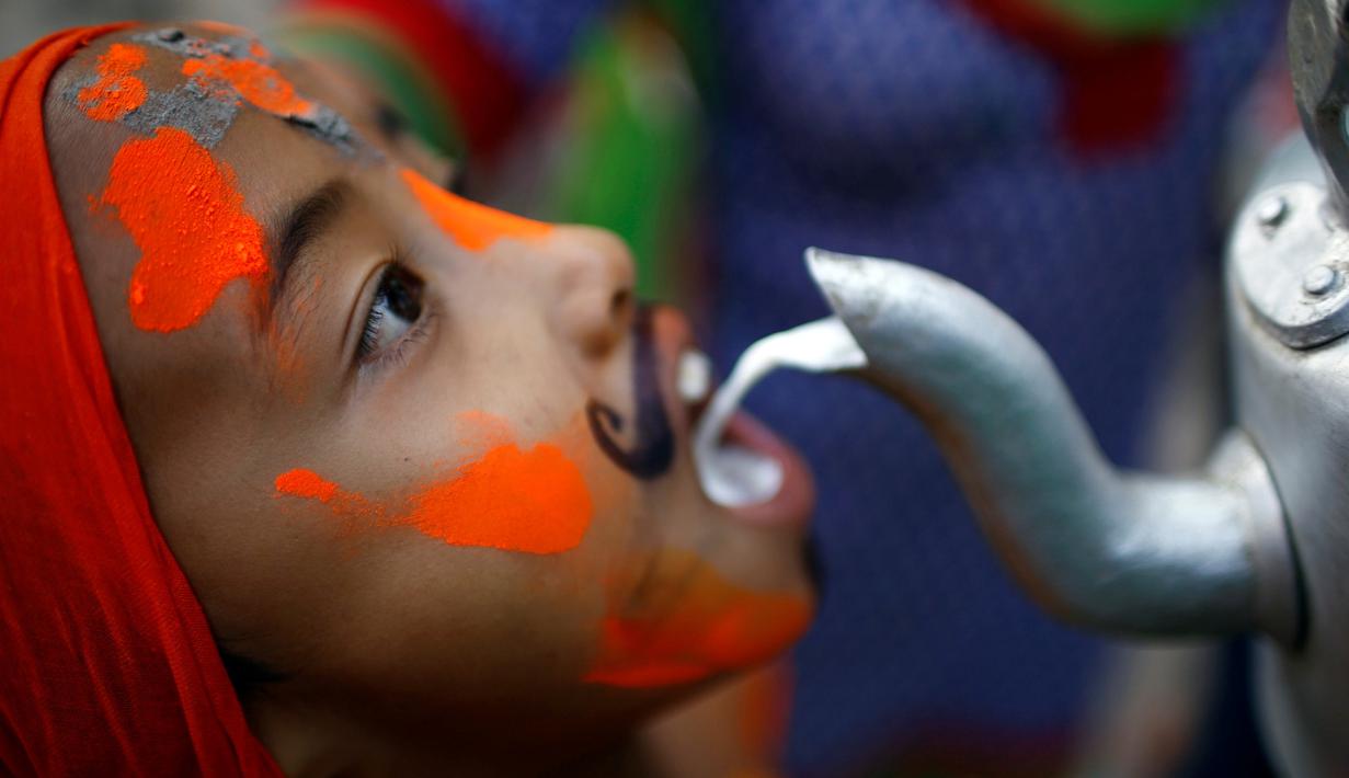 Seorang bocah membuka mulutnya untuk meminum susu saat perayaan Gaijatra Festival atau Festival Sapi di Kathmandu, Nepal, Jumat (19/8). Umat Hindu di Kathmandu merayakan Festival Sapi untuk meminta keselamatan dan kedamaian. (REUTERS/ Navesh Chitrakar)
