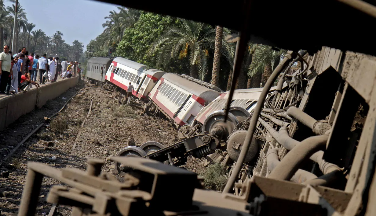 Sejumlah gerbong kereta penumpang usai tergelincir saat melintasi jalur di daerah al-Badrasheen, Giza, Mesir, (13/7). Dalam kejadian tersebut, tidak ada korban jiwa dan sekitar 55 penumpang terluka. (AFP Photo/Stringer)