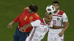 Bek Spanyol, Gerard Pique, duel udara dengan gelandang Maroko, Nabil Dirar, pada laga grup B Piala Dunia di Stadion Kaliningrad, Kaliningrad, Senin (25/6/2018). Kedua negara bermain imbang 2-2. (AP/Michael Sohn)