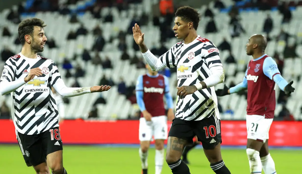 Pemain Manchester United, Marcus Rashford, melakukan selebrasi bersama Bruno Fernandes usai mencetak gol ke gawang West Ham United pada laga Liga Inggris di Stadion London, Minggu (6/12/2020). Setan Merah menang dengan skor 1-3. (Justin Setterfield/Pool Via AP)