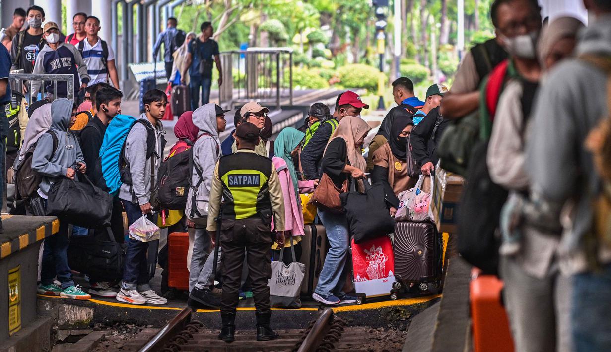 Para penumpang menyeberang rel saat bersiap naik kereta di stasiun Gubeng, Surabaya, Jawa Timur, Selasa 17 Maret 2026. PT Kereta Api Indonesia (KAI) Daop 8 Surabaya mencatat lonjakan penumpang pada masa angkutan Lebaran 2026. (JUNI KRISWANTO/AFP)