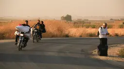 Warga melarikan diri menggunakan sepeda motor dan berjalan kaki saat pasukan Turki memburu milisi Kurdi di Ras al Ayn, Suriah, Rabu (9/10/2019). Presiden Turki Recep Tayyip Erdogan menamakan tindakan militer ini sebagai 'Operation Peace Spring'. (AP Photo/Baderkhan Ahmad)