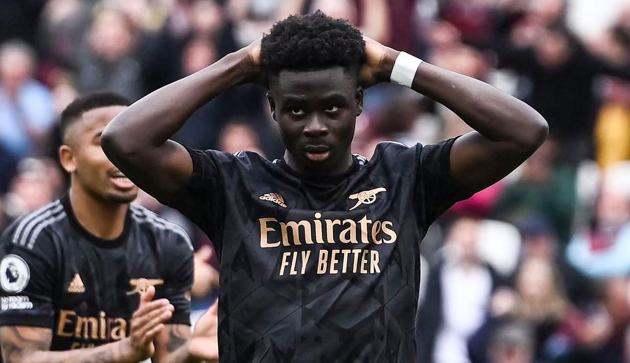 Reaksi kecewa pemain Arsenal, Bukayo Saka setelah gagal mencetak gol melalui tendangan penalti ke gawang West Ham pada laga lanjutan Liga Inggris 2022/2023 di London Stadium, London, 16 April  2023. Nasib The Gunners lagi-lagi seperti saat melawan Liverpool. Sempat unggul 2-0 melalui Gabriel Jesus dan Martin Odegaard. The Gunners sempat memiliki peluang untuk memperbesar kedudukan saat skor 2-1 melalui tendangan penalti Bukayo Saka. Bukannya mencetak gol, skuad asuhan Mikel Arteta tersebut malah membuang peluang dan tiga menit kemudian kebobolan melalui Jarrod Bowen. Laga pun kembali berakhir dengan skor 2-2. (AFP/Ben Stansall)