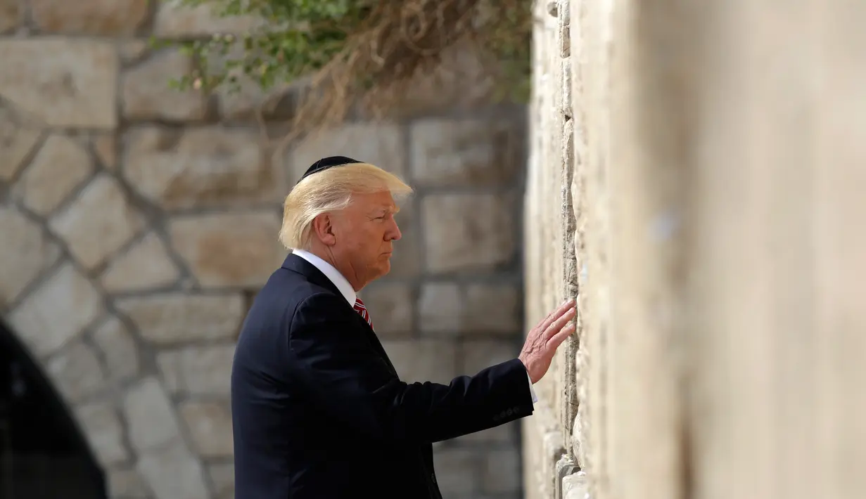 Presiden AS, Donald Trump mengunjungi Tembok Ratapan, tempat suci milik kaum Yahudi, di Yerusalem, Senin (22/5). Trump menatap sesaat tembok itu sebelum akhirnya memasukkan sebuah catatan di antara batu-batu monumental tersebut. (AP Photo/Evan Vucci)