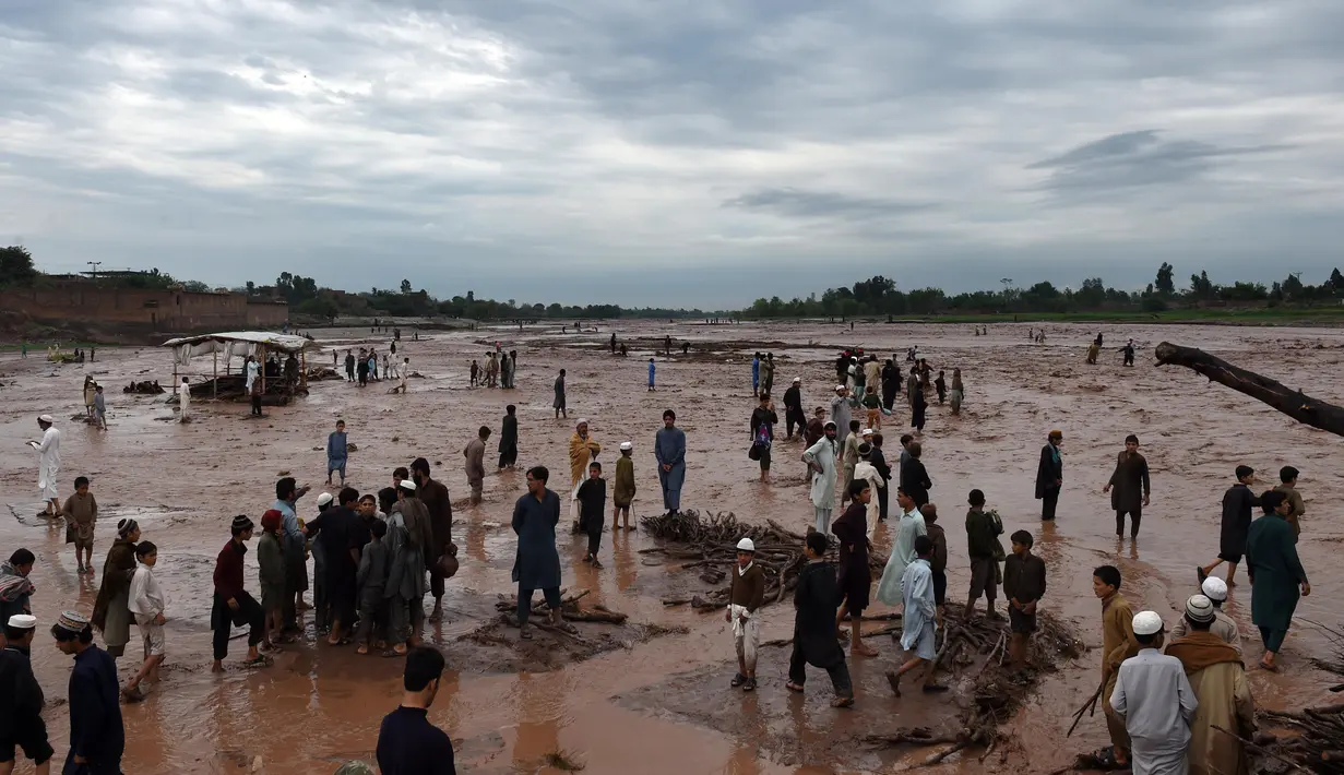 Warga terlihat pasrah melihat bangunan rumahnya hanyut tersapu banjir bandang di kawasan pasar di Peshawar, Pakistan, Minggu (3/4). Bencana yang menerjang wilayah Peshawar telah menghancurkan 852 rumah warga. (AFP/A Majeed)