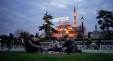 Orang-orang berbuka puasa selama bulan suci Ramadhan, di luar masjid Sultanahmet berlatar tulisan dalam bahasa Turki "Muhammad adalah utusan Allah", Istanbul, Turki, Rabu 25 Februari 2026. Sepanjang Ramadan, Masjid Sultanahmet di Istanbul, Turki, selalau ramai dikunjungi. (AP Photo/Emrah Gurel)