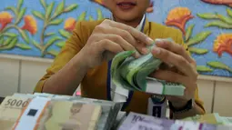 Teller menghitung uang pecahan kecil di kantor cabang Bank BJB di Melawai, Jakarta (7/6). Untuk mengantisipasi kebutuhan dan konsumsi saat berlebaran, pemerintah menyiapkan pasokan uang tunai tambahan tiap tahunnya. (Merdeka.com/Arie Basuki)