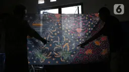 Perajin menunjukkan batik tulis di Sanggar Batik Kembang Mayang, Larangan, Tangerang, Banten, Minggu (19/7/2020). Rata-rata, lama pembuatan untuk selembar batik tulis adalah sekitar sebulan. (Liputan6.com/Angga Yuniar)