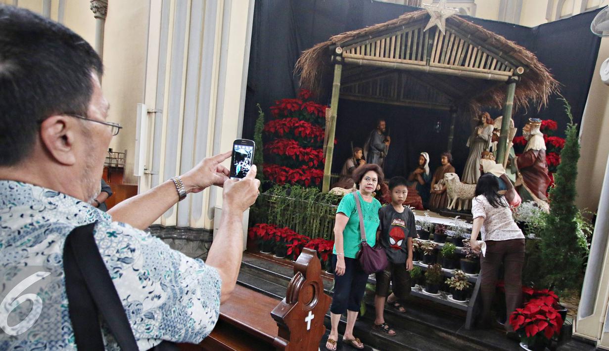 Pengunjung berfoto didekat diorama kelahiran Yesus Kristus di Gereja Katedral, Jakarta (23/12). Jelang perayaan Natal, Gereja Katedral mulai berhias dengan berbagai ornamen, salah satunya diorama kelahiran Yesus Kristus. (Liputan6.com/Immanuel Antonius)