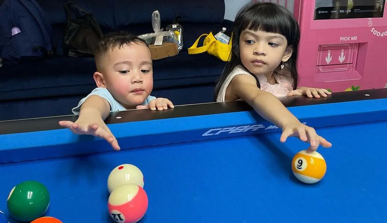 Keduanya asik bermain, seperti bermain bola billiard. Tampak Lembah pun menggerai rambutnya dengan poni depan menggemaskan dan mengenakan anting. [@riniperdiyanti]
