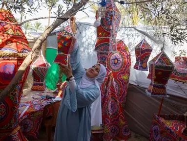Rehan Hazem Sharab, seorang pengungsi Palestina berusia 32 tahun, menggantung lampion buatan tangan yang terbuat dari kotak-kotak bantuan bekas saat bersiap menyambut bulan suci Ramadan, di luar tendanya di lingkungan Al-Mawasi, Khan Younis, di Jalur Gaza selatan pada Sabtu 7 Februari 2026. Menjelang bulan Ramadan, Rehan Hazem Sharab (32 tahun), seorang perempuan pengungsi yang tinggal di lingkungan Al-Mawasi, Khan Younis, Jalur Gaza selatan, mengubah kardus bantuan dan beberapa kain menjadi lampion Ramadan atau fanous. (Bashar Taleb/AFP)