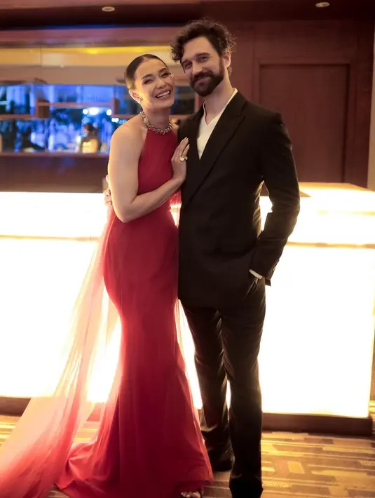 Di foto ini, Adinia tampil cantik memesona dalam balutan halter-neck dress berwarna merah. Dress ini memiliki train panjang yang menjuntai hingga ke lantai. Sedangkan Michael Wahr tampil sederhana dengan setelan jas-celana panjang berwarna hitam. Foto: Instagram.