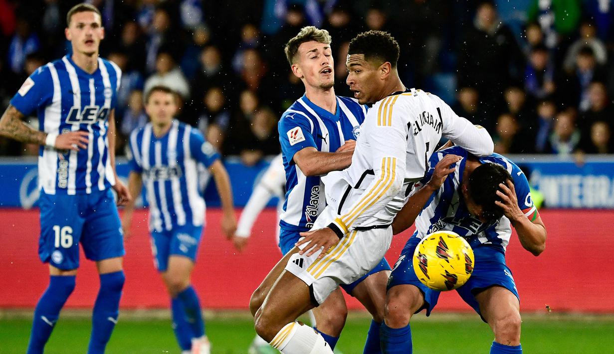 Pemain Real Madrid, Jude Bellingham (kedua kanan) berebut bola dengan sejumlah pemain Deportivo Alaves pada laga pekan ke-18 Liga Spanyol 2023/2024 di Mendizorroza Stadium, Vitoria, Spanyol, Jumat (22/12/2023) dini hari WIB. (AFP/Ander Gillenea)