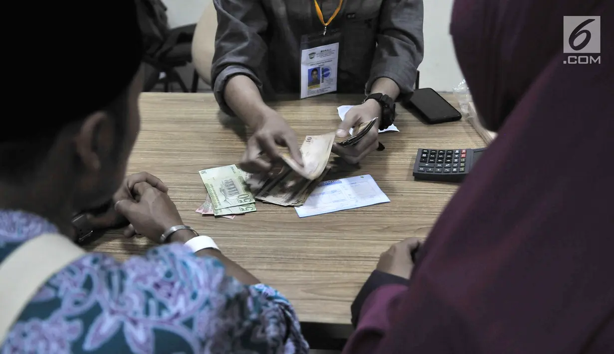 Petugas melayani calon jemaah haji yang menukarkan mata uang rupiah ke riyal di Asrama Haji Pondok Gede, Jakarta, Senin (22/7/2019). Embarkasi Haji Pondok Gede menyediakan layanan penukaran rupiah ke riyal untuk mempermudah calon jemaah haji sebelum bertolak ke Tanah Suci. (merdeka.com/IqbalNugroho)