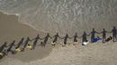 Orang-orang membuat barisan berpegangan tangan di sepanjang pantai Sao Conrado untuk berpelukan secara simbolis dengan laut pada Hari Laut Sedunia di Rio de Janeiro, Brasil, Kamis, 8 Juni 2023. (AP Photo/Bruna Prado)