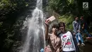 Wisatawan berswa foto di air terjun Cigentis, Kabupaten Karawang, Jabar, Kamis (29/6). Air terjun yang berada di kaki Gunung Sanggabuana tersebut menjadi salah satu tujuan wisata untuk mengisi libur lebaran. (Liputan6.com/Gempur M Surya)