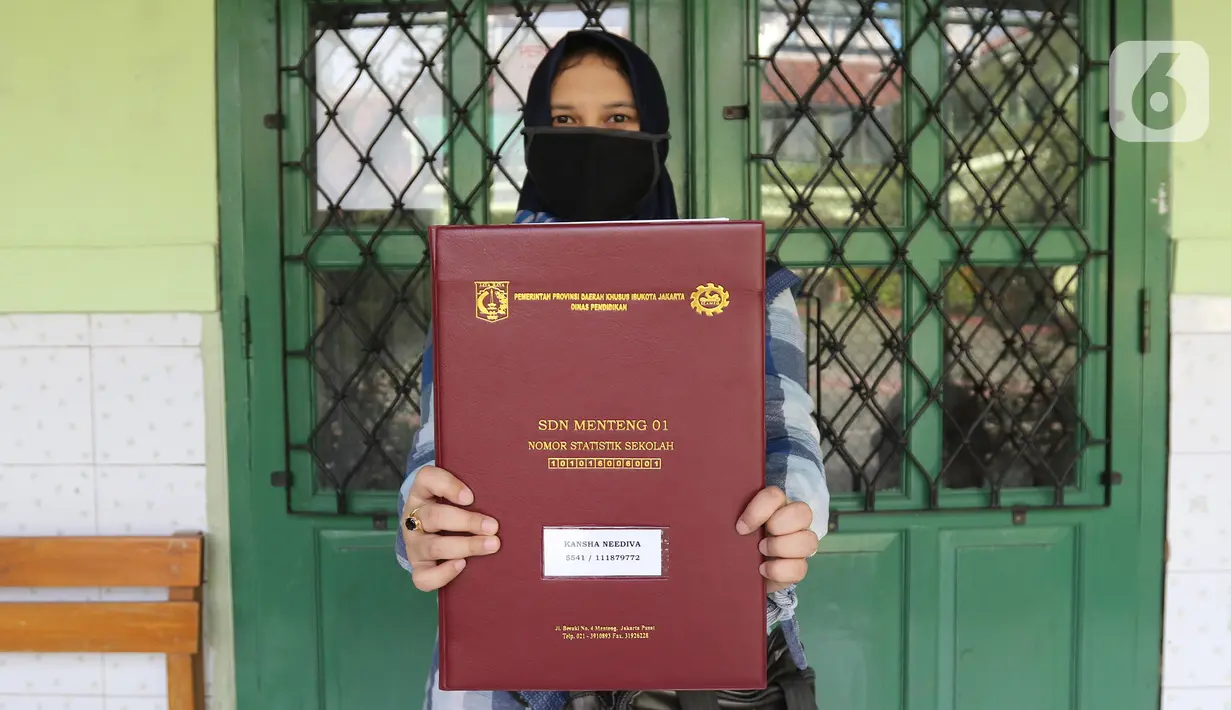 Wali murid menunjukkan laporan hasil belajar (rapor) kenaikan kelas di SD Negeri Menteng 01 Jakarta, Kamis (25/6/2020). Pembagian dilaksanakan mengikuti protokol kesehatan COVID-19 serta membagikan rapor secara bertahap dari 24-26 Juni 2020. (Liputan6.com/Herman Zakharia)
