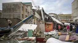 Beberapa orang berusaha mencari benda yang masih bisa dipergunakan diantara reruntuhan bangunan usai Topan Rammasun yang memporak-porandakan kota Zhanjiang di provinsi Guangdong, (20/7/2014). (REUTERS/Stringer)