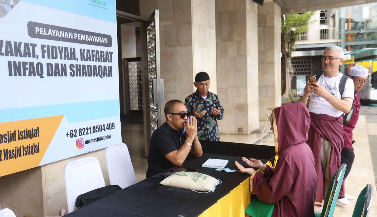 Zakat fitrah juga menjadi sarana berbagi agar fakir miskin dapat merasakan kebahagiaan di Hari Raya Idul Fitri. Tampak dalam foto, petugas Unit Pengelola Zakat (UPZ) melayani pembayaran zakat, fidyah, kafarat, infaq, dan shadaqah di teras Masjid Istiqlal, Jakarta, Minggu 15 Maret 2026. (Kapanlagi.com/Budy Santoso)