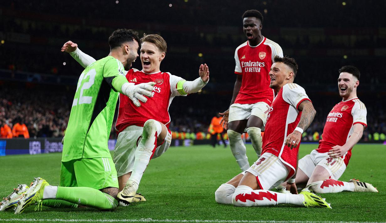 Pemain Arsenal merayakan kemenangan setelah David Raya berhasil menepis dua tendangan penalti dari pemain Porto pada laga leg kedua 16 besar Liga Champions 2023/2024 di Emirates Stadium, London, Inggris, Rabu (13/03/2024). (AFP/Adrian Dennis)