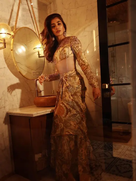 Bintang film Kisi Ka Bhai Kisi Ki Jaan (2023), Pooja Hegde, tampil glamor dengan Ghagra Choli nuansa emas dari @ritukumarhq  yang serasi dengan anting-antingnya. [@hegdepooja]