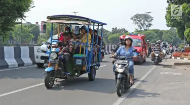 Sejumlah warga menaiki bak terbuka motor roda tiga menuju Kebun Binatang Ragunan di kawasan Jakarta, Minggu (9/6/2019). Selain melanggar aturan lalu lintas, perilaku tersebut juga sangat membahayakan keselamatan penumpang. (Liputan6.com/Herman Zakharia)