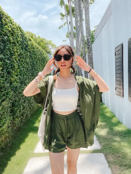 Gaya liburan auto-kece, pasangkan tank top putih basic kamu dengan set celana pendek tali serut dan outerwear (Foto: Instagram @danniasalsabilla)