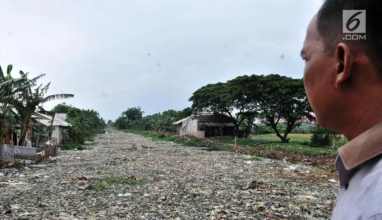 Warga melihat tumpukan sampah yang memenuhi Kali Pisang Batu di Tarumajaya, Kabupaten Bekasi, Jawa Barat, Rabu (9/1). Tumpukan sampah tersebut berasal dari limbah rumah tangga. (Merdeka.com/Iqbal S Nugroho)