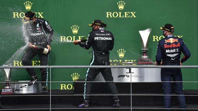 Pembalap Mercedes Lewis Hamilton (tengah) melakukan selebsasi usai menempati posisi pertama Formula 1 Grand Prix di Spa-Francorchamps, Spa, Belgia, Minggu (30/8/2020). Posisi kedua dan ketiga diisi pembalap Mercedes Valtteri Bottas serta pembalap Red Bull Max Verstappen. (John Thys, Pool via AP)