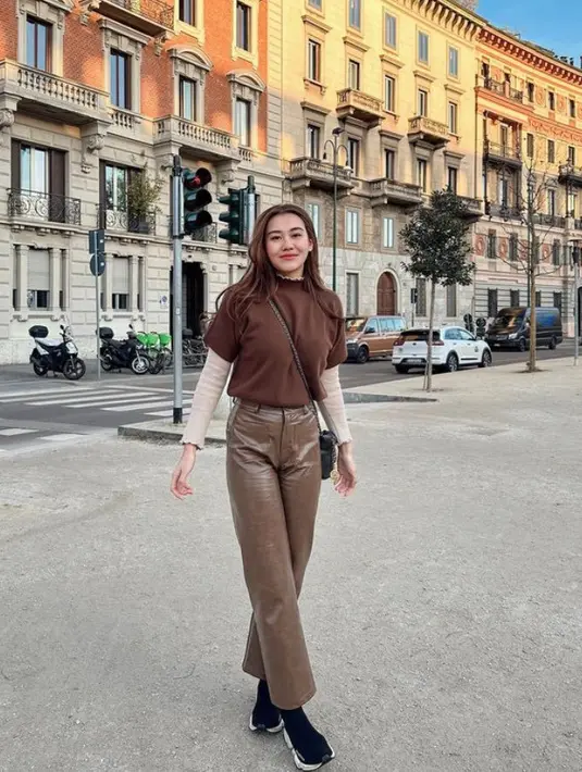 Aaliyah Massaid tampil mengenakan atasan lengan pendek warna coklat dipadukan inner lengan panjang dan celana panjang kulit warna coklat. Dengan sneaker dan sling bag hitam. [@aaliyah.massaid]