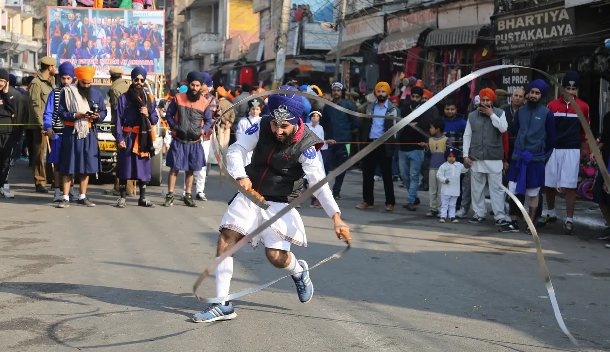 Seorang pria melakukan atraksi bermain senjata saat prosesi keagamaan menjelang ulang tahun kelahiran Guru Gobind Singh di Jammu, India (2/1). Guru Gobind Singh secara resmi menjadi pemimpin orang Sikh pada umur kesembilan. (AP Photo / Channi Anand)