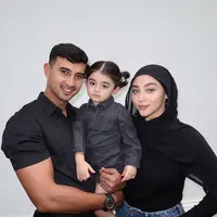 Bersama kedua orangtuanya, Guzel tampil menggemaskan bak boneka. Ia kenakan jumpsuit black denim dengan rambut ikat dua [@guzelimalisyakieb]