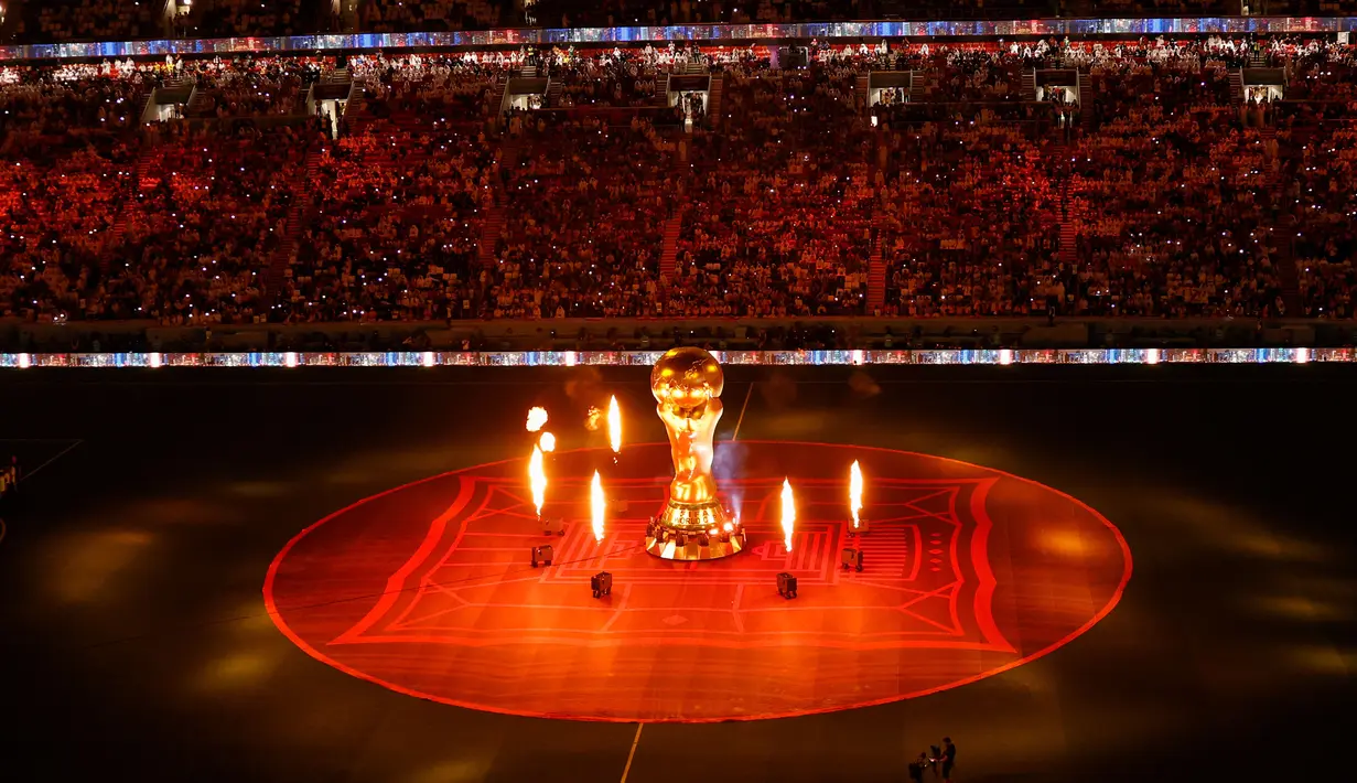 Replika trofi Piala Dunia FIFA terlihat di lapangan saat kembang api meledak menjelang pertandingan sepak bola Grup A Piala Dunia Qatar 2022 antara Qatar dan Ekuador di Stadion Al-Bayt di Al Khor, utara Doha (20/11/2022). Acara dimulai pada pukul 21.40 WIB dengan berlangsung megah dan meriah.(AFP/Odd Andersen)