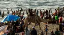 Warga Palestina naik unta mengelilingi pantai Kota Gaza, Jumat (22/6). Pantai Gaza menjadi pelipur bagi penduduk yang tak punya pilihan berwisata ke luar kota atau luar negeri. (AFP PHOTO/MAHMUD HAMS)