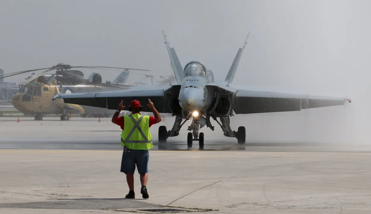Petugas bandara saat memberi aba - aba kepada  pesawat jet 188 Hornet yang akan lepas landas untuk mengikuti Canadian International Air Show di Bandara Pearson, Toronto, Kamis (3/9/2015). Acara ini biasanya digelar selama tiga hari. (REUTERS/Louis Nastro)