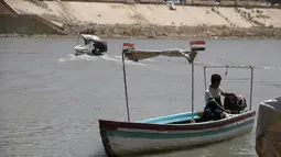 Para pria mengemudikan kapal feri kayu di sepanjang sungai Tigris saat permukaan air sungai semakin dangkal, di pusat ibu kota Irak, Baghdad, pada 26 Mei 2022. Ketinggian air di dua sungai utama Irak telah menurun secara signifikan dalam beberapa tahun terakhir, menjadi tantangan besar yang dihadapi negara semi-gurun berpenduduk 41 juta jiwa itu. (AHMAD AL-RUBAYE/AFP)